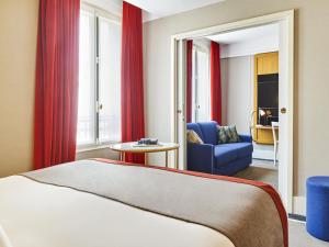 a hotel room with a bed and a blue chair at l'Echiquier Opéra Hotel Paris - MGallery Collection in Paris