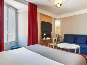 a bedroom with a bed and a couch and a table at l'Echiquier Opéra Hotel Paris - MGallery Collection in Paris +136 photos
