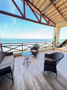 a balcony with chairs and a table and the ocean at Casa da Maré Pé na areia Suítes climatizadas e deck vista mar in Icapuí