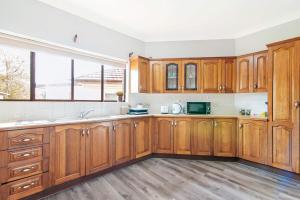 a kitchen with wooden cabinets and a large window at Cozy King Single Room - Near Station & Olympic Park - Shared Bathroom in Rookwood Station +26 photos