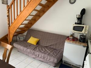 un canapé dans un salon sous un escalier dans l'établissement Maisonnette charmante - Proche plage et commerces - FR-1-482-161, à Royon