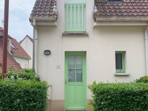 une maison blanche avec une porte et des fenêtres vertes dans l'établissement Maisonnette charmante - Proche plage et commerces - FR-1-482-161, à Royon