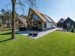 a house with a pitched roof on a lawn at Thatched bungalow with private terrace in Schaluinen