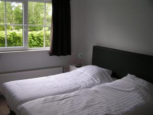 a bedroom with a white bed with two windows at Spacious 10-Person Villa in Quiet Holiday Park in Schaluinen