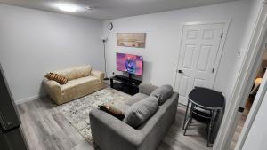 a living room with a couch and a tv at Cozy Oasis in the Greens in Regina