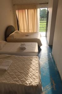 a group of three beds in a room with a window at Casa Finca La Catalina - Tu escape cerca de la ciudad in Montería