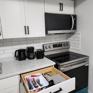 a kitchen with a stove and a drawer with a box at Cozy Oasis in the Greens in Regina +11 photos