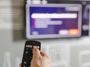 a person holding a remote control in front of a tv at ibis Cambridge Central Station in Cambridge