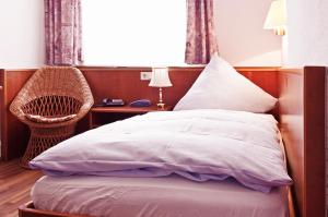 a bedroom with a bed and a chair and a window at Hotel Restaurant Knechtstedener Hof in Dormagen