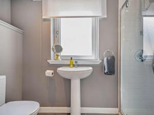 a bathroom with a sink and a toilet and a window at 4 Bed in Lamlash 94809 in Brodick +13 photos