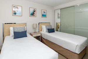two beds sitting next to each other in a room at 5-Star Beachfront Retreat with Theatre & Pool in Mooloolaba +51 photos