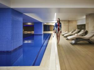 a woman walking down a hallway with a swimming pool at Mövenpick Hotel Istanbul Bosphorus in Istanbul