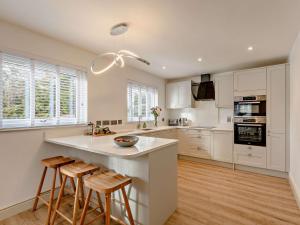a kitchen with white cabinets and a island with bar stools at 4 Bed in Embleton 89964 in Christon Bank