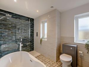 a bathroom with a tub and a toilet at 4 Bed in Embleton 89964 in Christon Bank +5 photos
