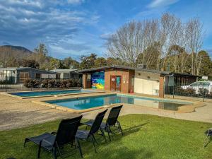 a house with a pool and chairs in the grass at BIG4 Breeze Holiday Parks - Eildon in Eildon