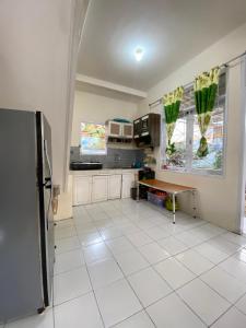 cocina con nevera y suelo de baldosa blanca en Villa Fathan bukit cipendawa, en Cianjur
