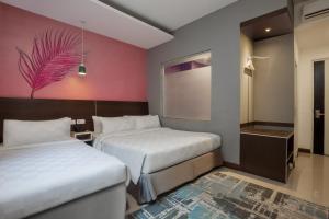 a bedroom with two beds and a pink wall at Avery Kusumanegara Yogyakarta in Demangan +14 photos