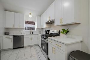 a white kitchen with white cabinets and appliances at Modern 3BR in Bishop Arts Walk to Shops in Dallas