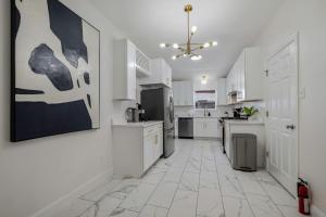 a kitchen with white cabinets and a large painting on the wall at Modern 3BR in Bishop Arts Walk to Shops in Dallas