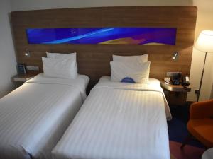 a hotel room with two beds and a chair at Novotel Taiping in Taiping