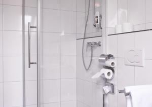 a bathroom with a shower with a roll of toilet paper at Hotel Restaurant Knechtstedener Hof in Dormagen