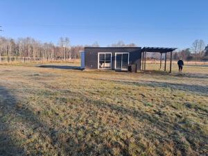 une vache debout dans un champ à côté d'un hangar dans l'établissement La tiny de cuinco, à La Unión