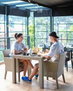 two people sitting at a table in a restaurant at Orbit88 Hotel by AMR in Kandy