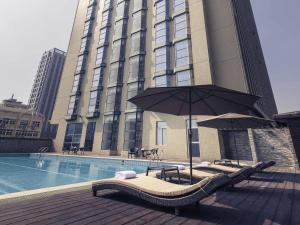 a large building with a pool and an umbrella at Mercure Xiamen Exhibition Centre in Xiamen