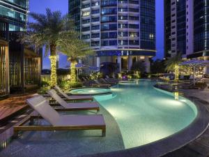 a swimming pool with lounge chairs and a building at Sofitel Kuala Lumpur Damansara in Kuala Lumpur