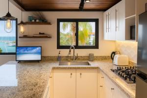 a kitchen with a sink and a flat screen tv at Ocean & Marina views,Affordable,Spoil yourself! in Puerto Aventuras