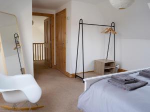 a bedroom with a white bed and a white chair at 1 Bed in Kinlochbervie 86897 in Rhiconich