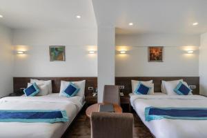 two beds in a hotel room with blue and white pillows at Palette - Silver Leaf in Vapi +49 photos
