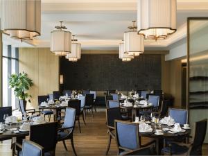 a dining room with tables and chairs and chandeliers at Pullman Zhouzhuang in Kunshan