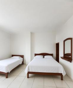 a white bedroom with two beds and a mirror at Hotel Pedernales MrRobert in Pedernales