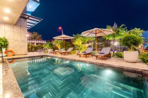 - une piscine avec chaises longues et parasols la nuit dans l'établissement Dương Villa, à Hội An