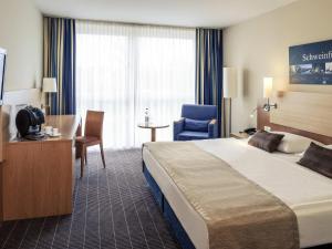 a hotel room with a bed and a desk and chair at Mercure Hotel Schweinfurt Maininsel in Schweinfurt