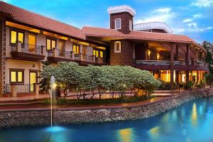 a large building with a pond in front of it at Hudson Resorts in Pondūr