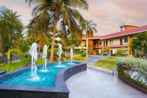 a fountain in a pool in front of a building at Hudson Resorts in Pondūr