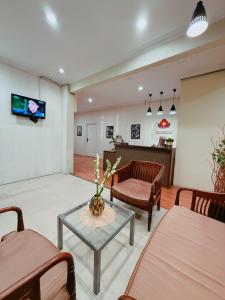 a living room with chairs and a table and a tv at URVANA Hotel By Majestra Hospitality in Kamparganya
