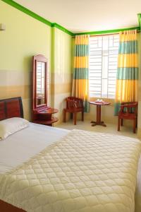 ein Schlafzimmer mit einem Bett und einem Tisch und einem Fenster in der Unterkunft Bình Minh Hotel Ninh Thuận in Ninh Hải