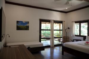 a bedroom with two beds and a table and windows at Buddha Resort in Catagnan