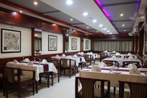 a dining room with white tables and chairs at Mayor Hotel in Siliguri