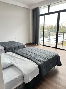 a bedroom with two beds and a large window at Casa Laguna in Trujillo
