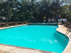 a large blue swimming pool with trees in the background at Paseo Verde Beach Resort in Laiya