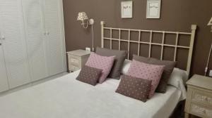 1 dormitorio con cama blanca y almohadas rosas en Residencial la Gomera en Puertito de Güímar
