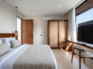 a bedroom with a large bed and a television at La Finca Bingin in Uluwatu