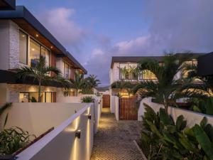 a house with a white fence and palm trees at La Finca Bingin in Uluwatu