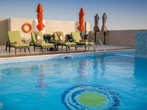a pool at a hotel with chairs and umbrellas at Gulf Pearls Hotel in Doha
