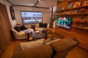 a living room with a tv and a couch and tables at Cinema Resorts 3 in Motobu