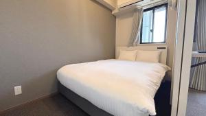 福岡市にあるLiving like hotel Hakata Premiumの小さなベッドルーム(窓、白いベッド付)